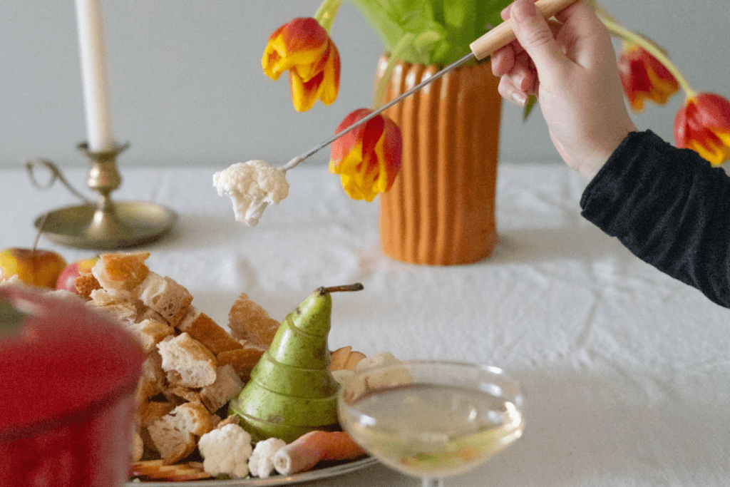 Klassinen juustofondue lisukkeineen, leipää, kasviksia ja hedelmiä