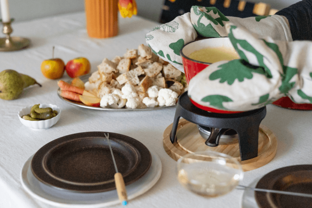 Klassinen juustofondue katettuna pöytään lisukkeiden ja valkoviinin kanssa